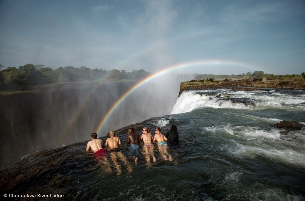 The main curtain of Victoria Falls with a rainbow arcing through the spray
